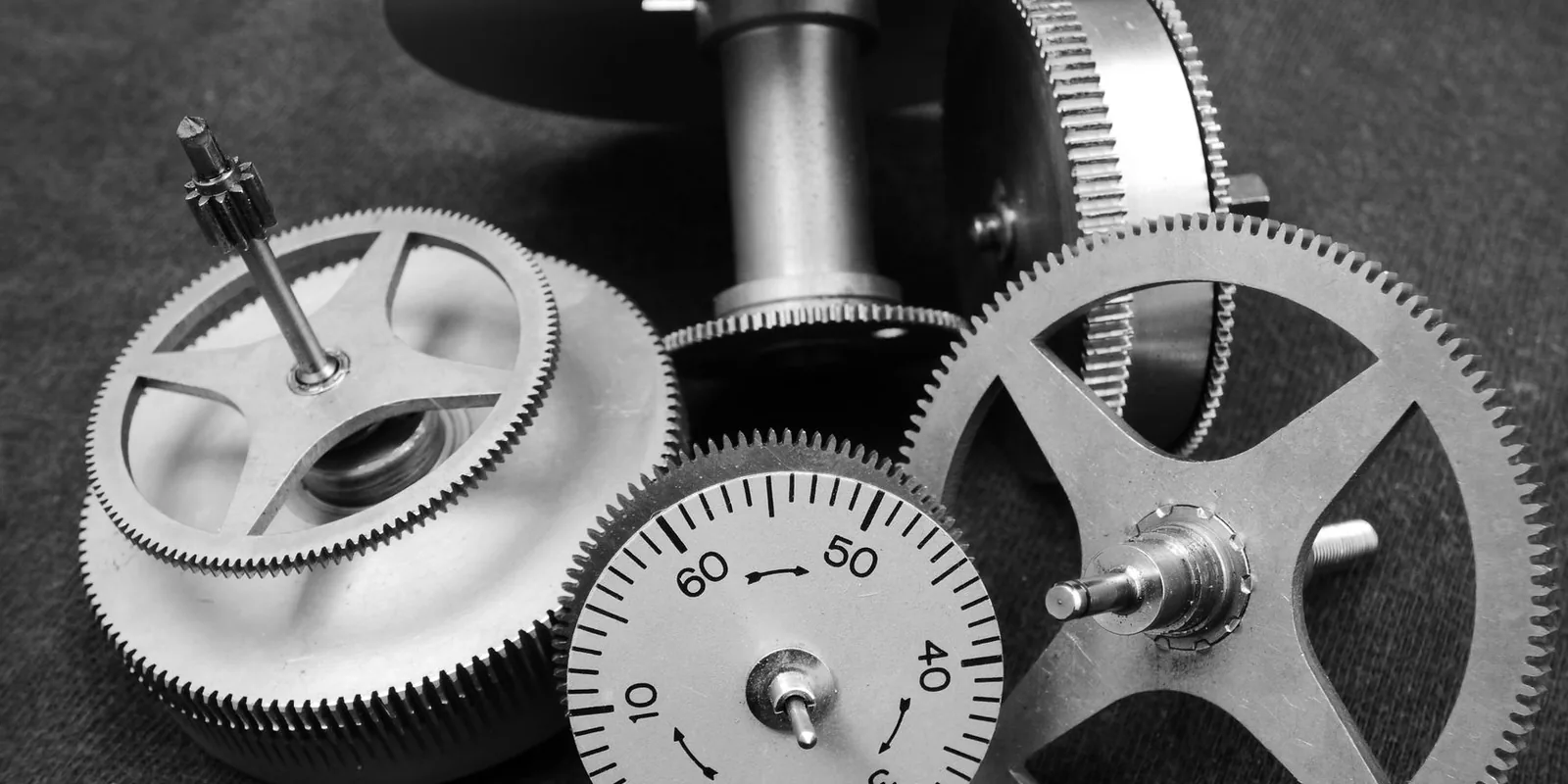 Detailed black and white image of various metal gears in a mechanical setup