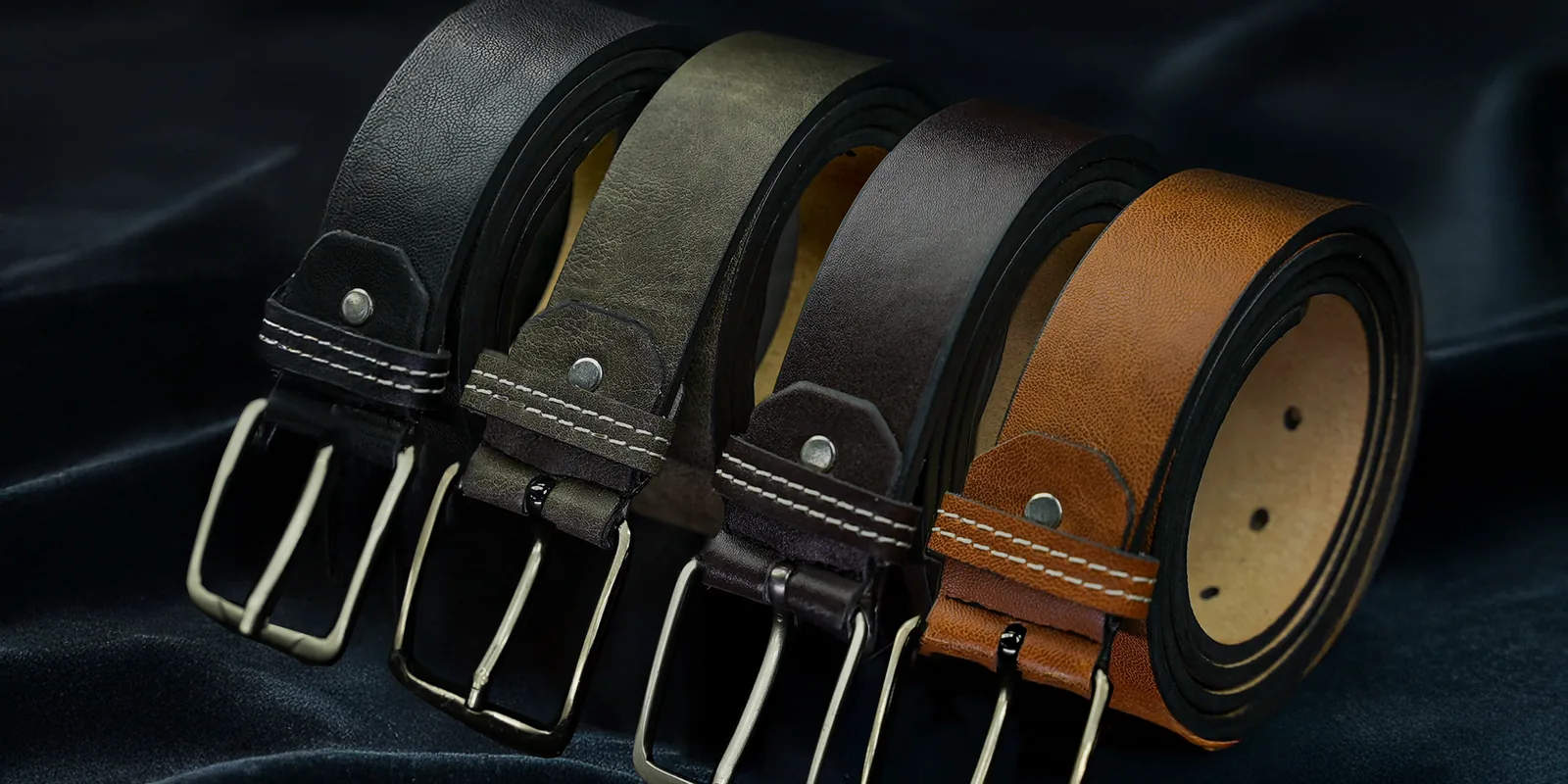 Set of luxurious leather belts in black, grey, brown, and tan on elegant fabric background