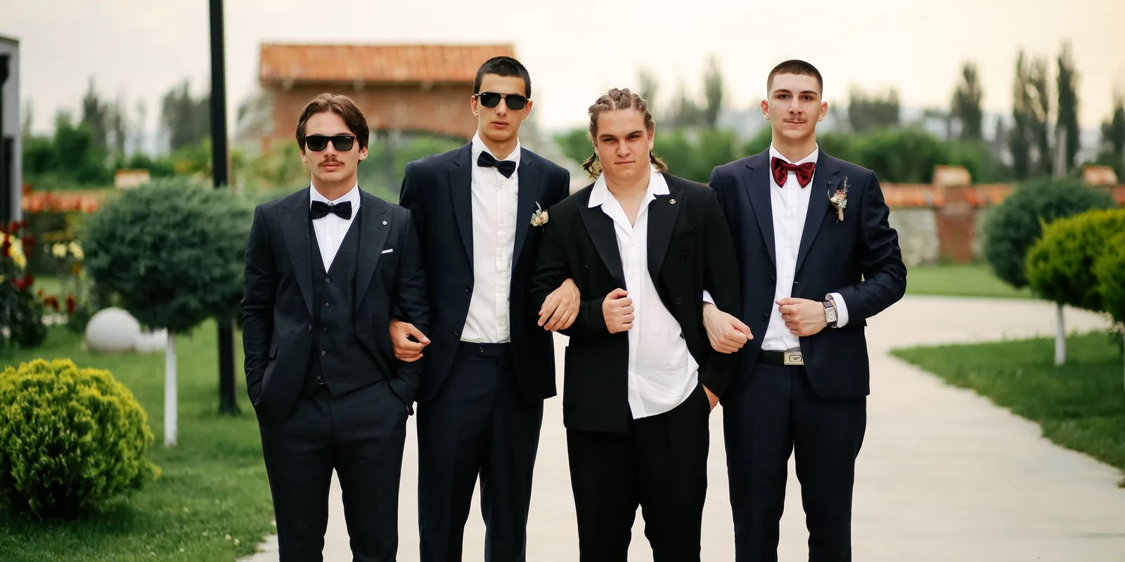 Group of well-dressed groomsmen posing outdoors in formal suits