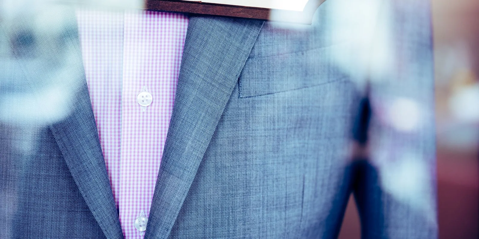 Elegant gray suit with a pink patterned shirt displayed in a store window, showcasing formal attire