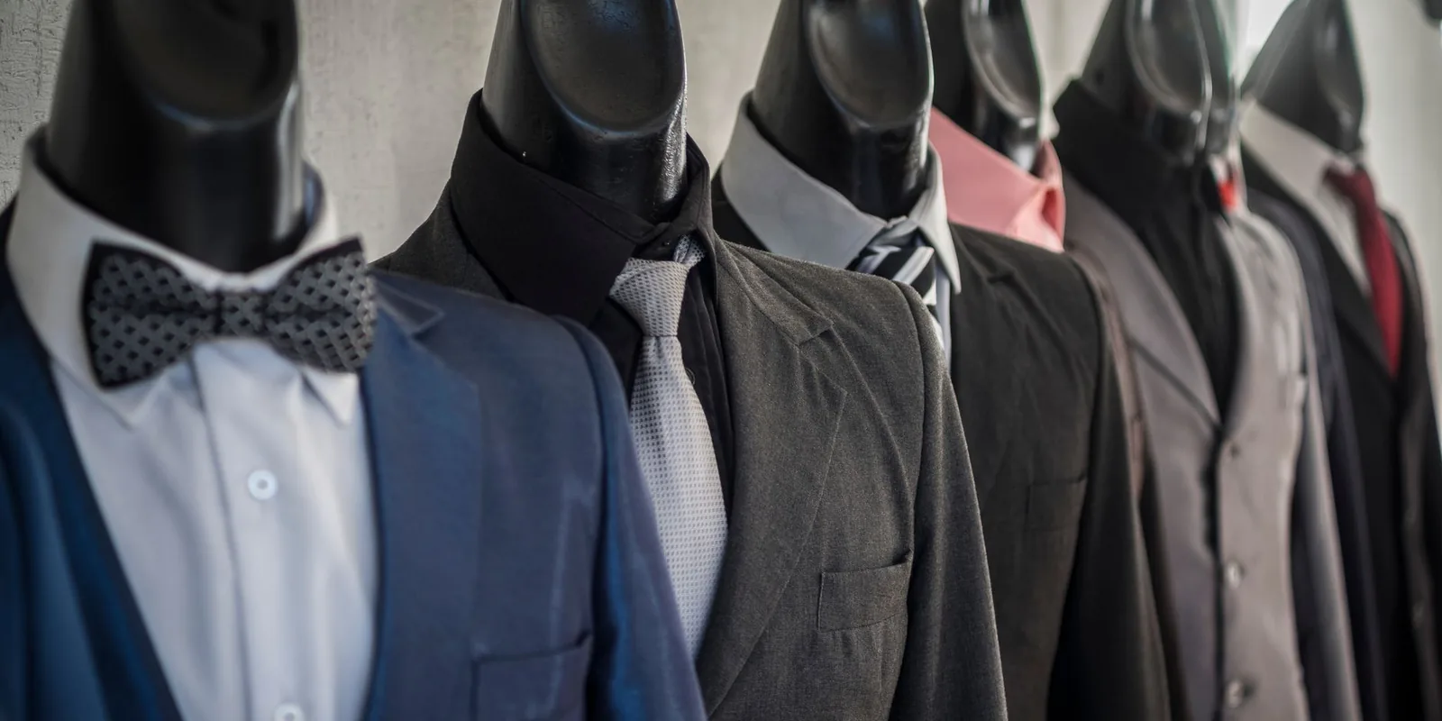 Close-up of mannequins adorned in elegant men's suits in a store setting, showcasing diverse styles