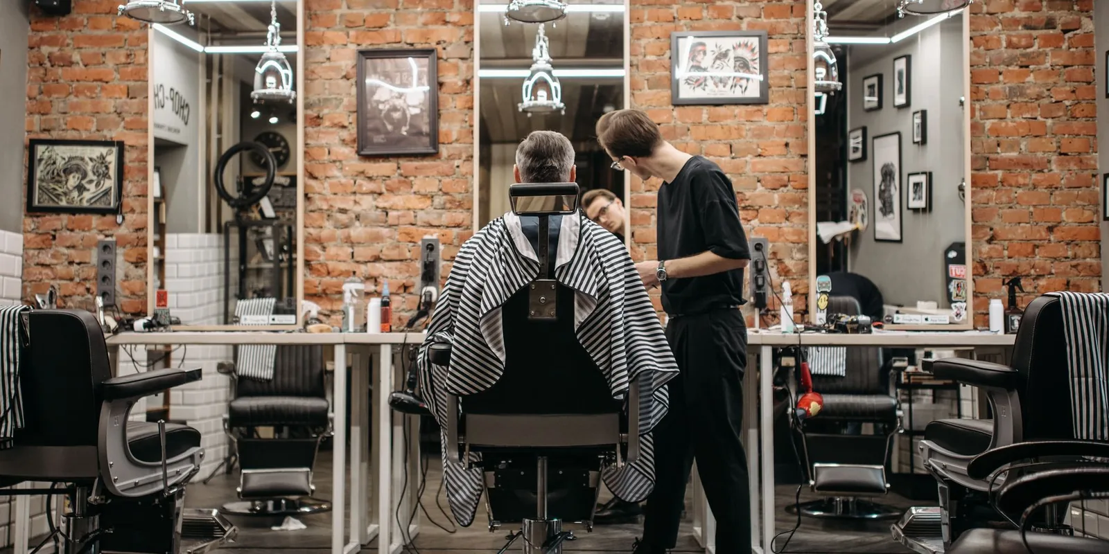A skilled barber attending to a client in a stylish barbershop with exposed brick walls