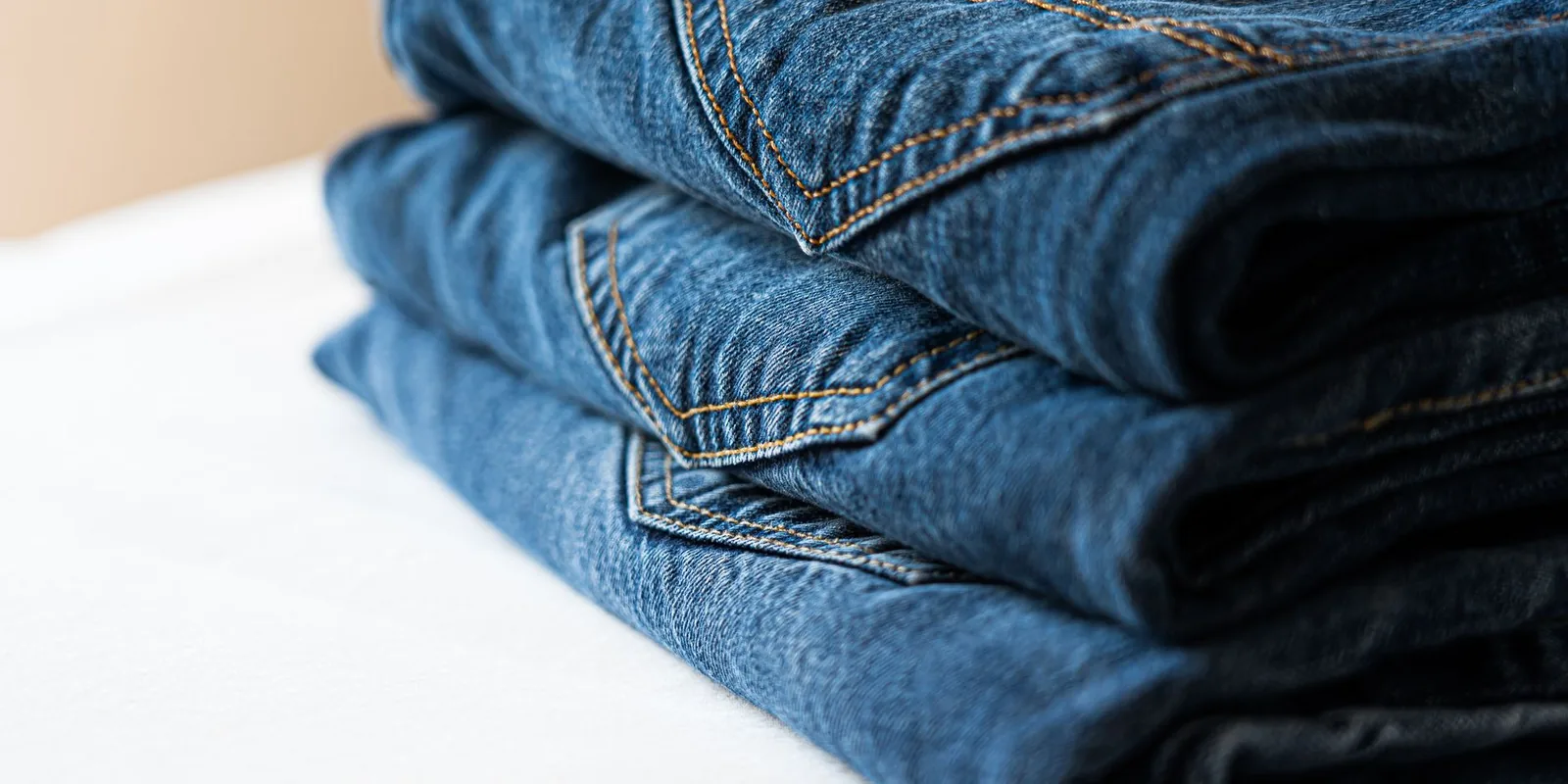 Stack of neatly folded blue denim jeans highlighting stitching details