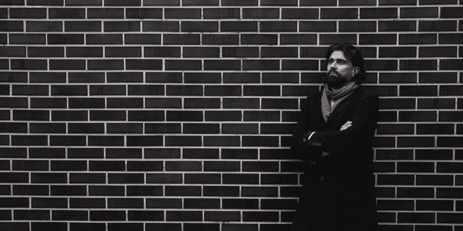 Man standing pensively against a brick wall outdoors in Lithuania