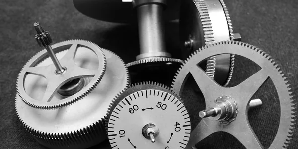 Detailed black and white image of various metal gears in a mechanical setup