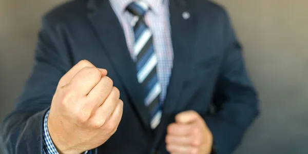 Close-up of a businessman in a suit showing determination with a fist