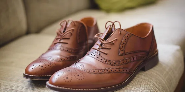 Elegant brown pair of leather shoes for men placed on gray surface at home