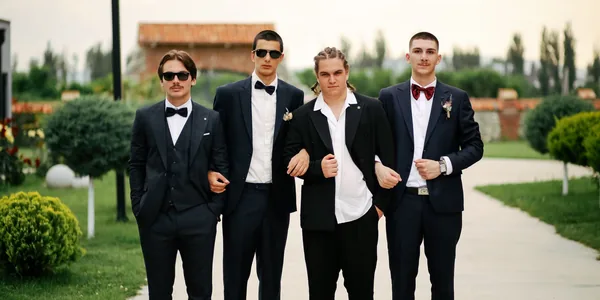 Group of well-dressed groomsmen posing outdoors in formal suits