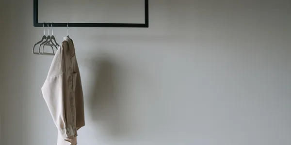 A beige blazer hangs on a minimalist metal rack, providing a serene and stylish wardrobe aesthetic