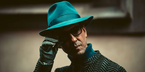 Close-up of a fashionable man in Milan wearing a teal hat and sunglasses