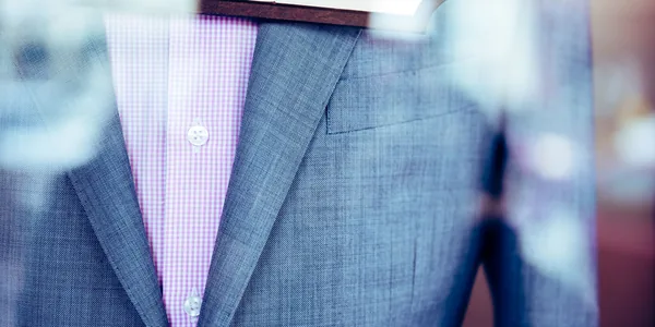 Elegant gray suit with a pink patterned shirt displayed in a store window, showcasing formal attire