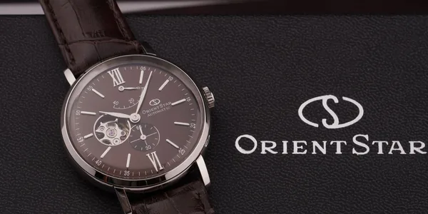 Close-up of an elegant Orient Star wristwatch with a brown leather strap on a textured box