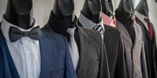 Close-up of mannequins adorned in elegant men's suits in a store setting, showcasing diverse styles