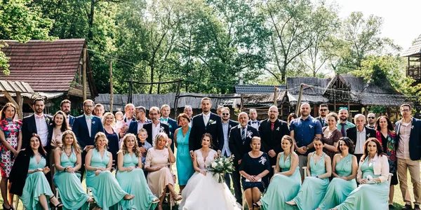Large group photo of wedding guests outdoors on a sunny day