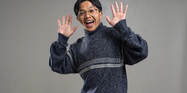 Cheerful person wearing a stylish sweater, posing with hands raised and a joyful expression