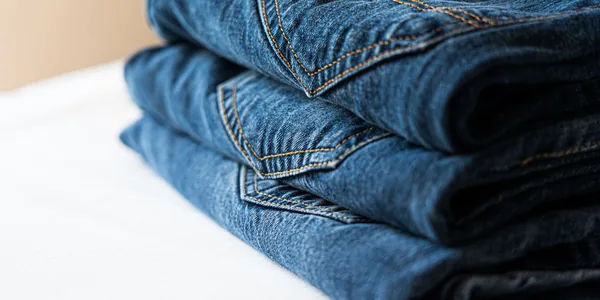 Stack of neatly folded blue denim jeans highlighting stitching details