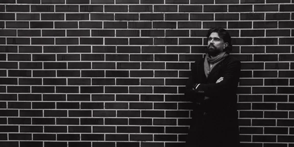 Man standing pensively against a brick wall outdoors in Lithuania