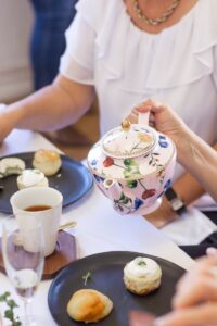 person holding white and blue floral ceramic teapot