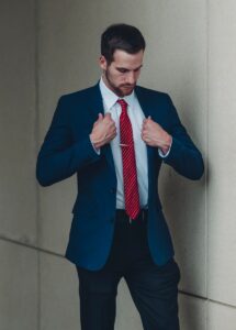 a man in a suit and red tie tying his tie