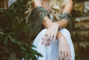 A lady sitting in a white skirt and green crocheted cardigan